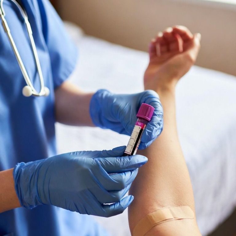 A healthcare professional draws blood from a patient's arm with a blood collection tube.