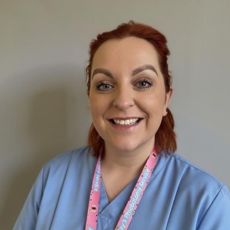 Photo of Megan Smiling woman in a blue shirt, wearing a lanyard, against a neutral background.